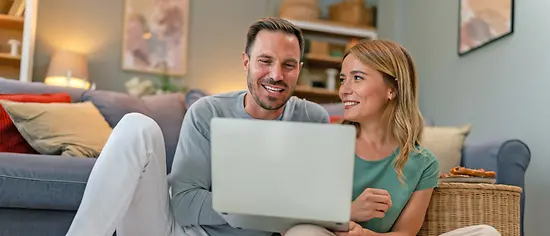 Ein glückliches Paar vergleicht Zahnzusatzversicherungen auf einem Laptop.
